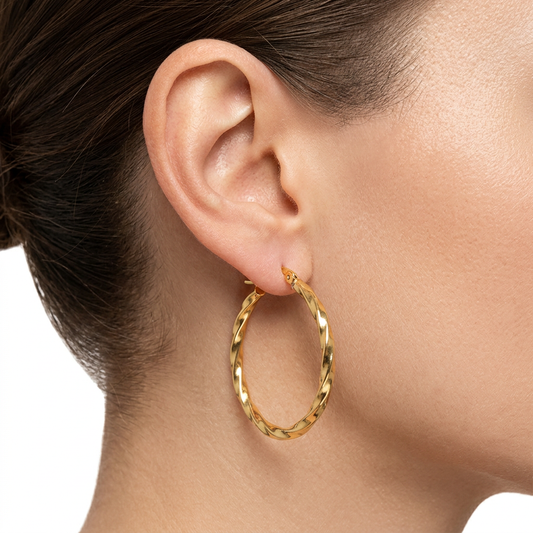 Złoty kolczyk kółko ze skręconym wzorem na modelce na białym tle