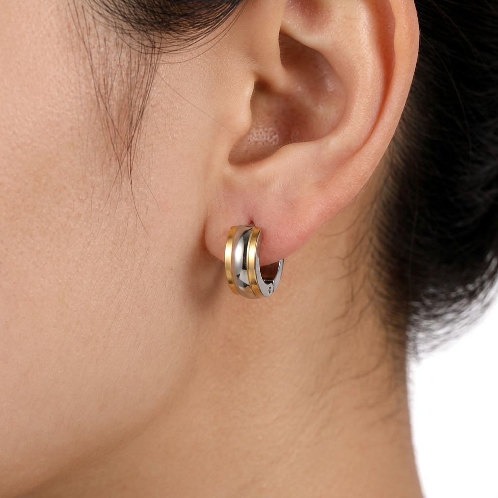 Złoty kolczyk 4 × 11 mm na uchu modelki na białym tle